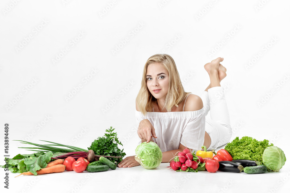 Beautiful blond woman in white clothes and lots of fresh vegetables on white background Beautiful blond woman in white clothes and lots of fresh vegetables on white background