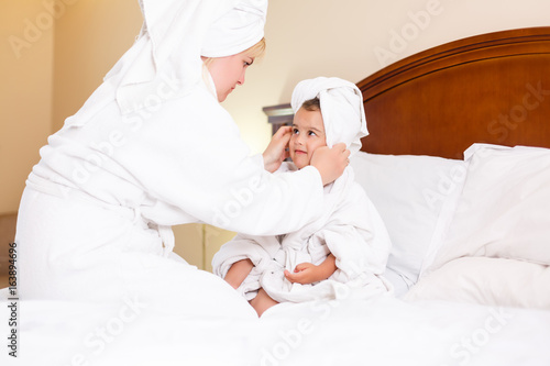 mother and daughter in head towels after shower in bed at home