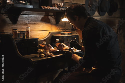 Handsome man shoemaker at footwear workshop.