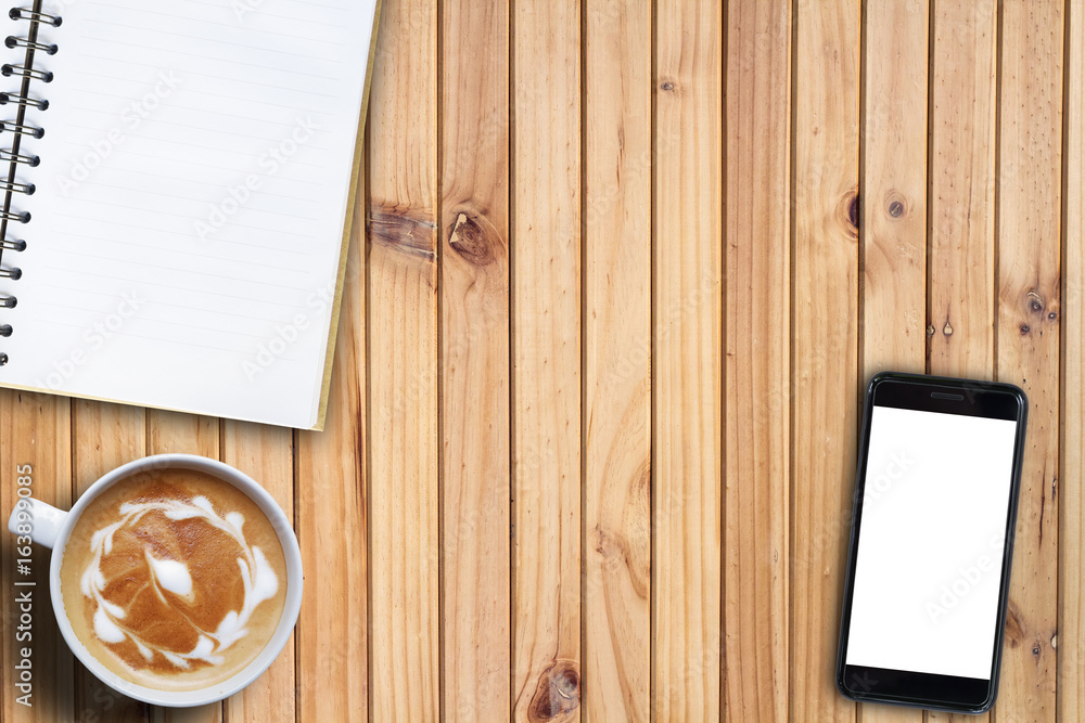 Mock up cell phone blank screen and note book and hot coffee on desk. high angle view. copy space business concept Mock up cell phone blank screen and note book and hot coffee on desk. high angle view. copy space business concept