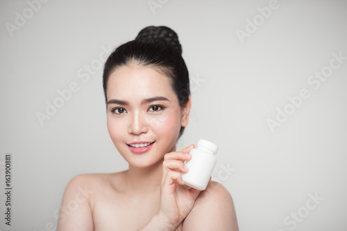 Healthy happy asian woman with pills bottle in hand.