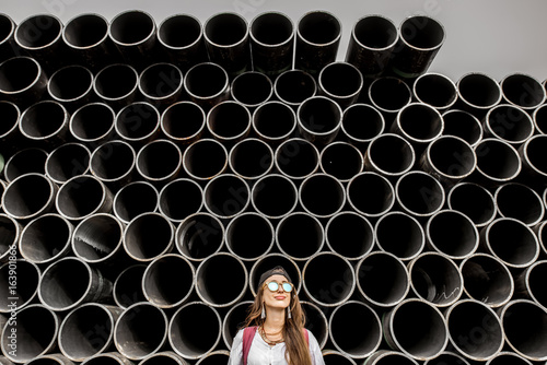 Young woman on the stack of iron tubes background