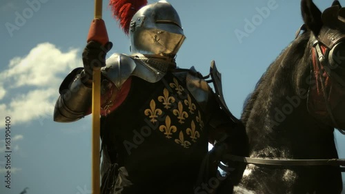 Medieval knight with lance riding horse to joust tournament