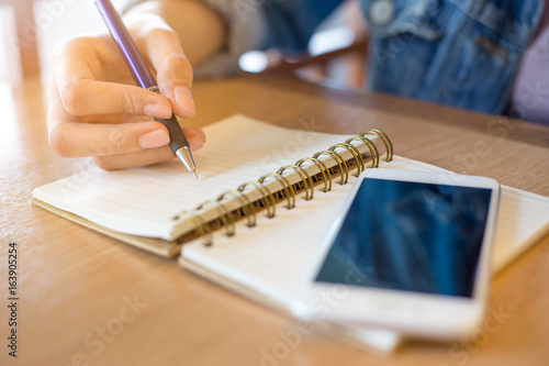 Wallpaper Mural woman's hands writing in spiral notepad placed on wooden desk. Torontodigital.ca