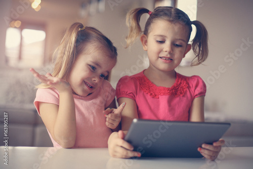 Two little sisters using tablet.