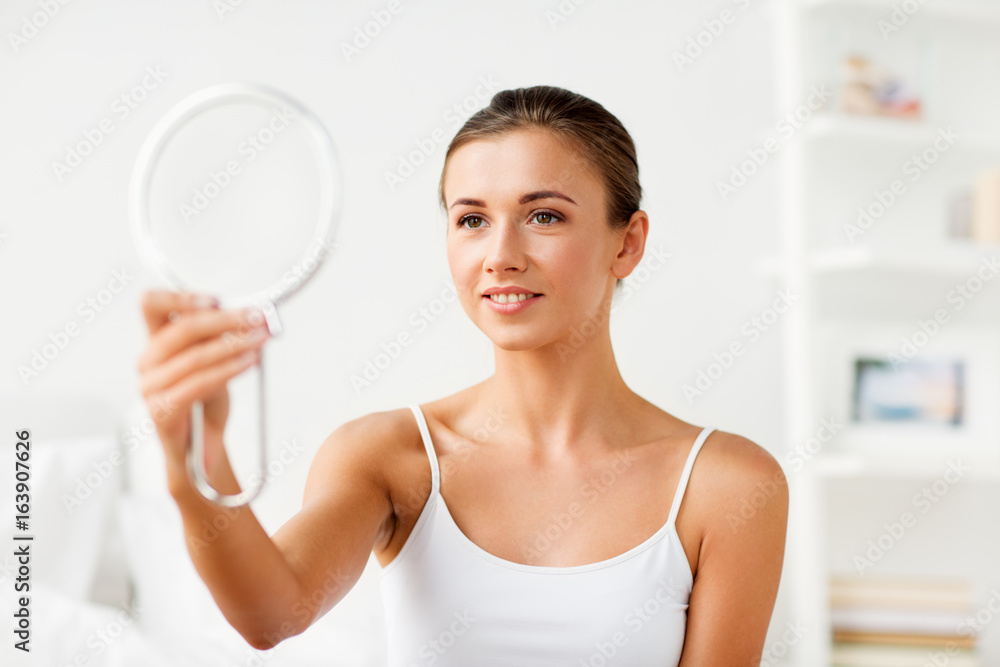 beautiful woman with mirror sitting on bed at home