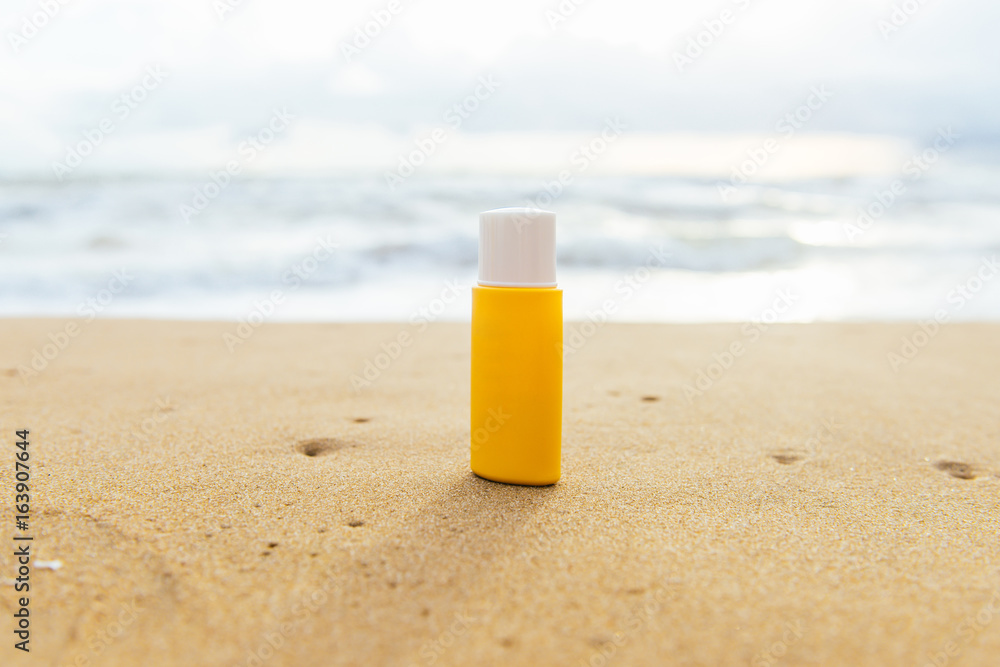 Summer sunbath. Sun lotion bottle in the sand Summer sunbath. Sun lotion bottle in the sand