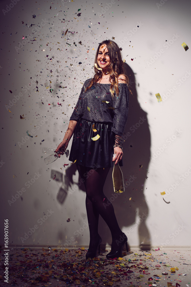 Naklejka premium Woman posign. Home party. Lot of confetti around her.