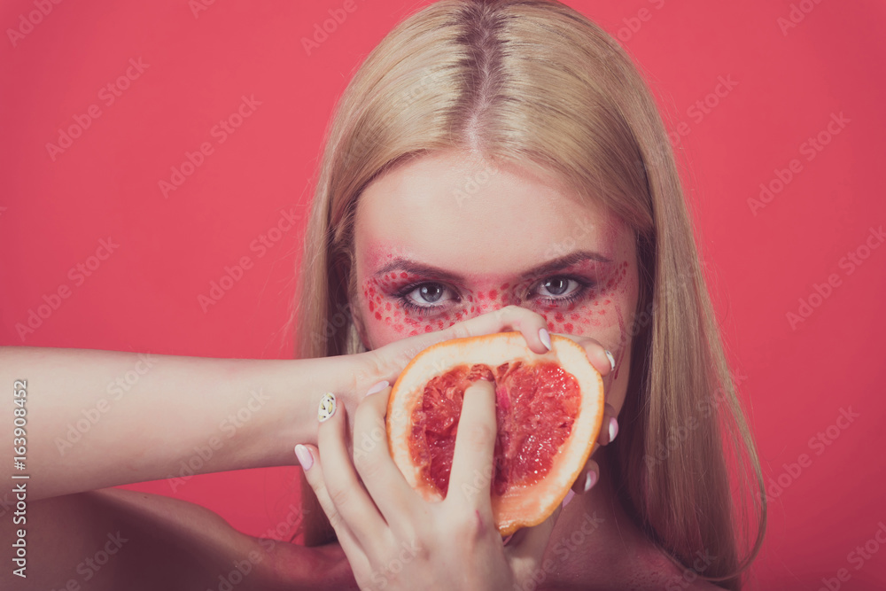 grapefruit in hands of woman with creative fashionable makeup, vitamin grapefruit in hands of woman with creative fashionable makeup, vitamin