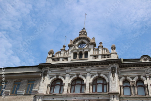 Building, roof, roof skate, clock on the roof, sky, clouds, architecture, house, windows, stucco