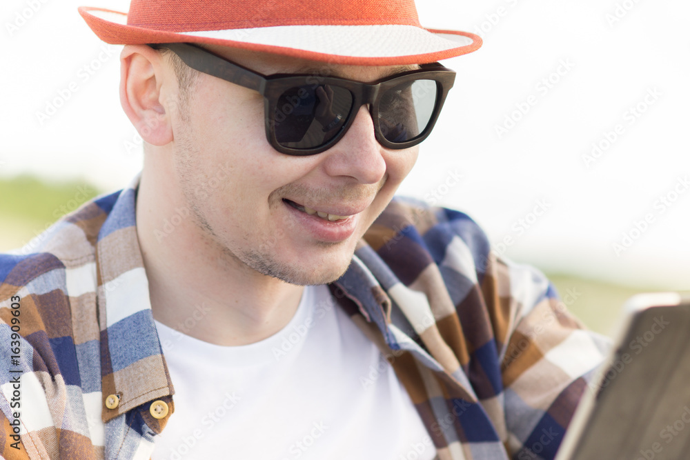 A man in smart casual hipster style with tablet combining work with relax on the beach of Baltic Sea A man in smart casual hipster style with tablet combining work with relax on the beach of Baltic Sea