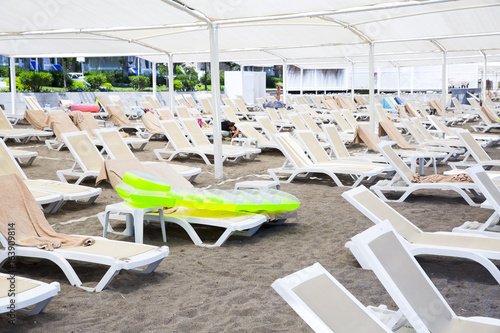 White plastic sunbeds in sandy beach under big parasol photo