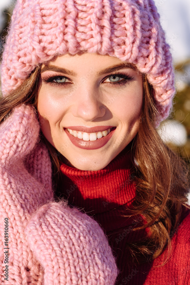 close up Winter portrait of a Happy candid beautiful young lady in a pink knitted beanie hat and gloves close up Winter portrait of a Happy candid beautiful young lady in a pink knitted beanie hat and gloves