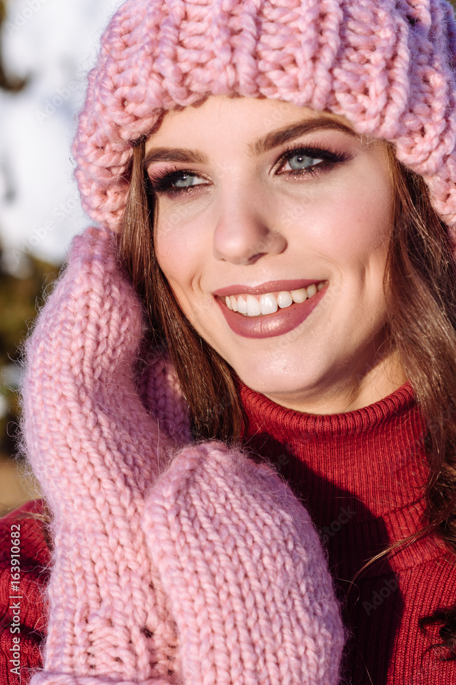close up Winter portrait of a Happy candid beautiful young lady in a pink knitted beanie hat and gloves close up Winter portrait of a Happy candid beautiful young lady in a pink knitted beanie hat and gloves