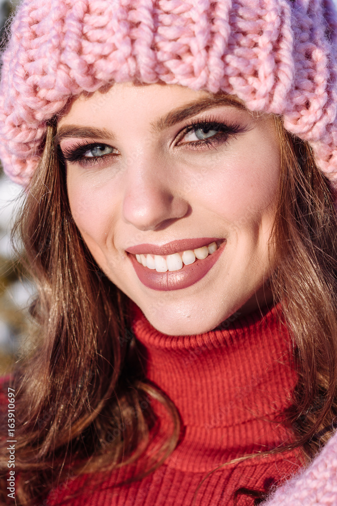 close up Winter portrait of a Happy candid beautiful young lady in a pink knitted beanie hat and gloves close up Winter portrait of a Happy candid beautiful young lady in a pink knitted beanie hat and gloves