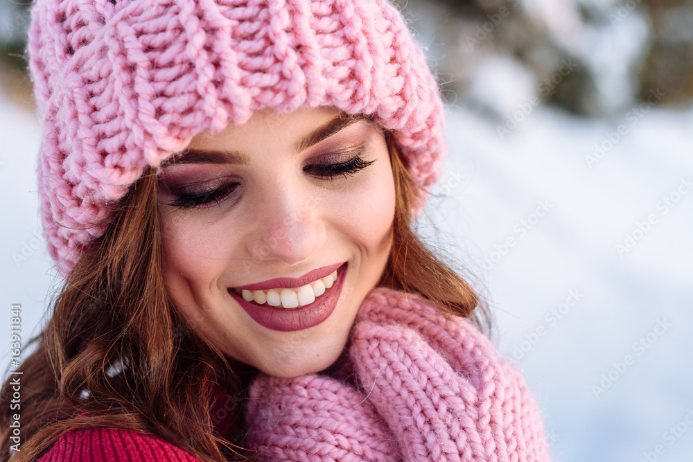 close up Winter portrait of a Happy candid beautiful young lady in a pink knitted beanie hat and gloves close up Winter portrait of a Happy candid beautiful young lady in a pink knitted beanie hat and gloves