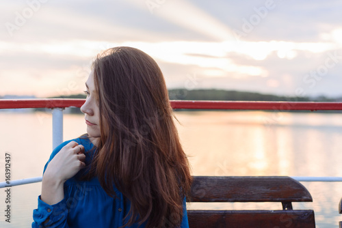 Summer happy portrait beautiful woman girl caucasian asian blended in blue shirt posing on background sky lake water sunset long hair brunette outdoors photo