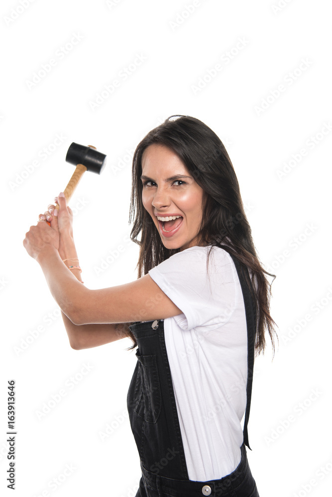 Emotional brunette girl holding hammer and smiling at camera isolated on white