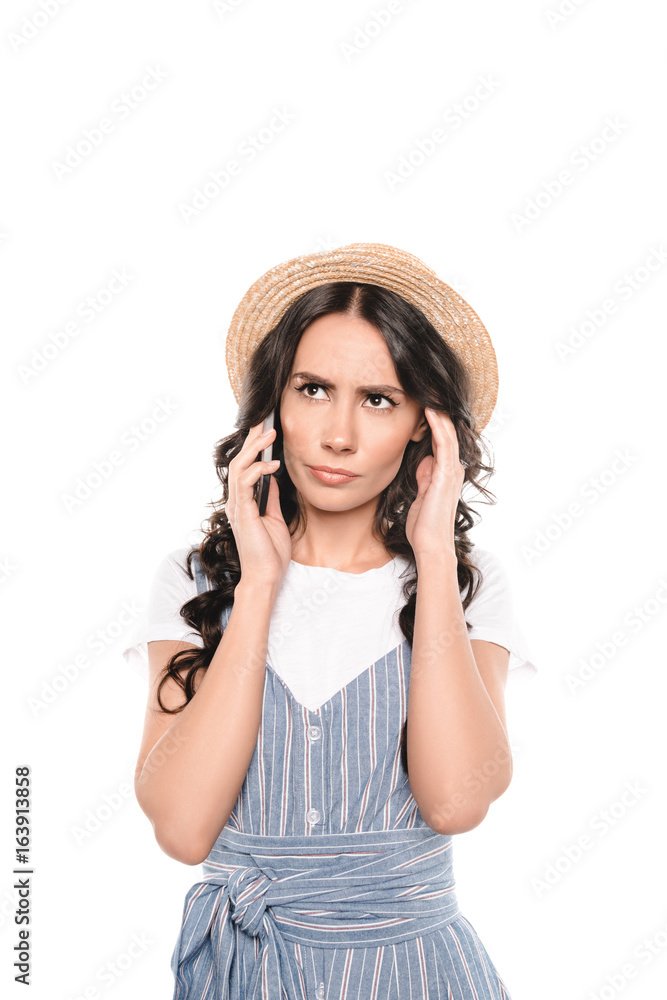 Serious young woman in straw hat talking on smartphone isolated on white Serious young woman in straw hat talking on smartphone isolated on white