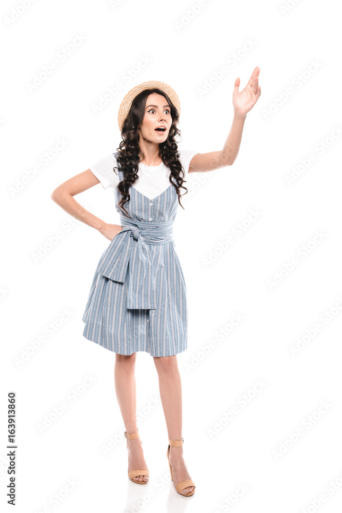 Shocked young woman in dress and straw hat waving hand and looking away isolated on white