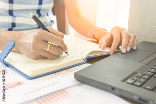 Businessman check seriously analyzes a financial reports and writing on notebook on wooden table at office ,Finance managers task,Concept business and finance planing management.