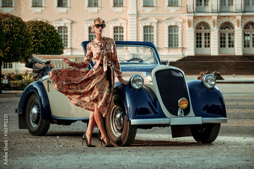 Beautiful lady with bag near classic convertible © Nejron Photo