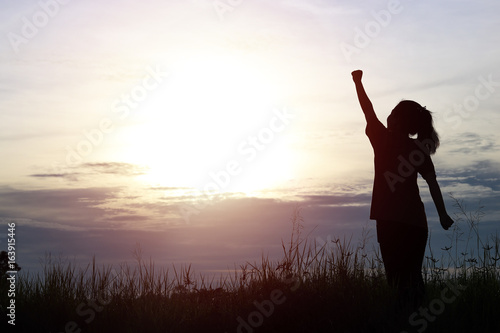 silhouette of women posing and showing hand on sky in twilight, concept as thinking, analyzing about business and success in working at sunset