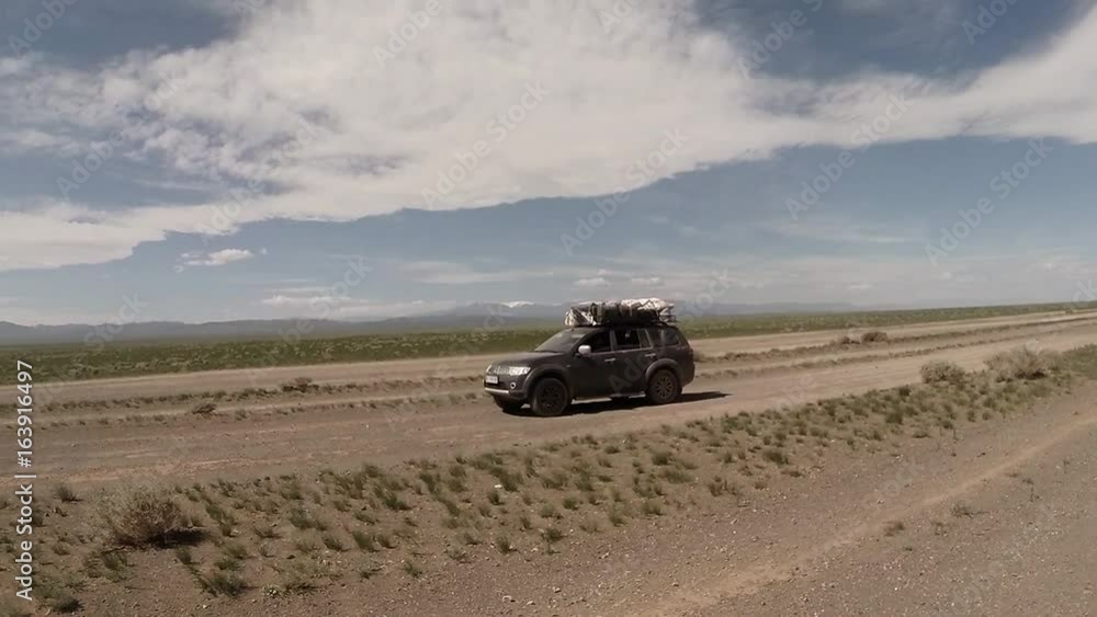 Black Suv on a Dirt Road in the Mongolian Desert and Camels Black Suv on a Dirt Road in the Mongolian Desert and Camels