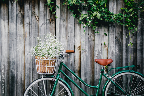 Bicycle against wooden fence with flowers in basket  photo