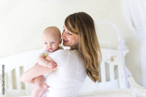 Young mother holding her newborn child on the baby room