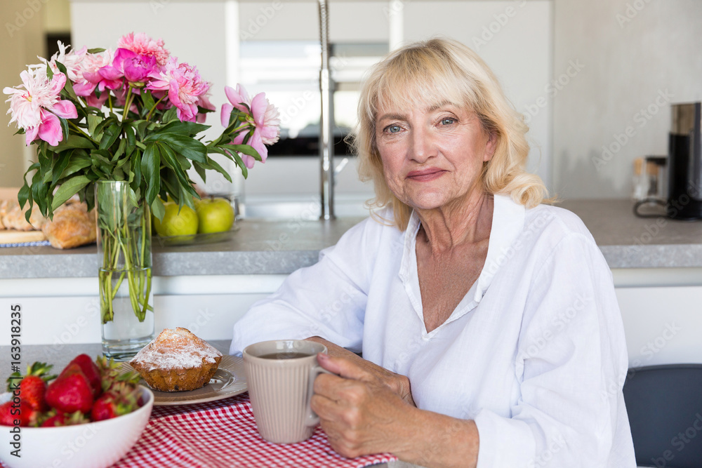 Smiling mature lady sitting with cup of coffee Smiling mature lady sitting with cup of coffee