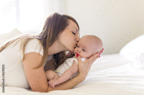 Portrait of mother with her 3 month old baby in bedroom