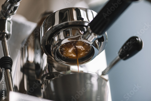 The process of making coffee step by step. Delicious freshly ground morning espresso coffee with a beautiful crema pouring through the bottomless (naked) portafilter into a grey cup. Horizontal photo