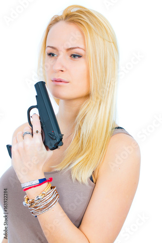 Blonde young woman in short skirt with gun on white background