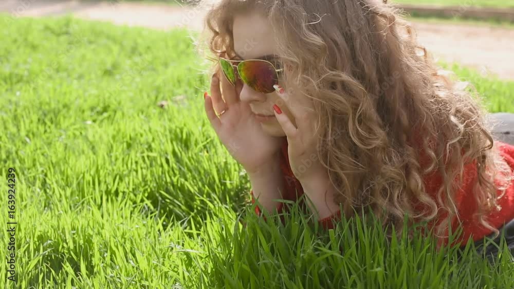Happy smiling woman lying on green grass enjoying life, young female having fun outdoors in spring park. Happy smiling woman lying on green grass enjoying life, young female having fun outdoors in spring park.