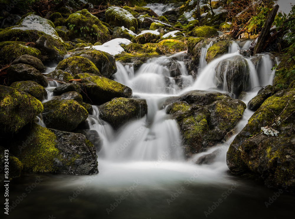 Blurred waterfall through mossy rocks