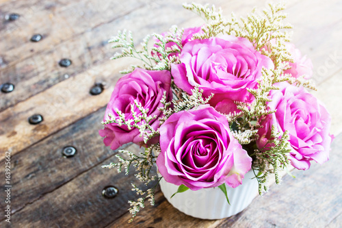 Violet roses in vase on wood table with soft focus , blured