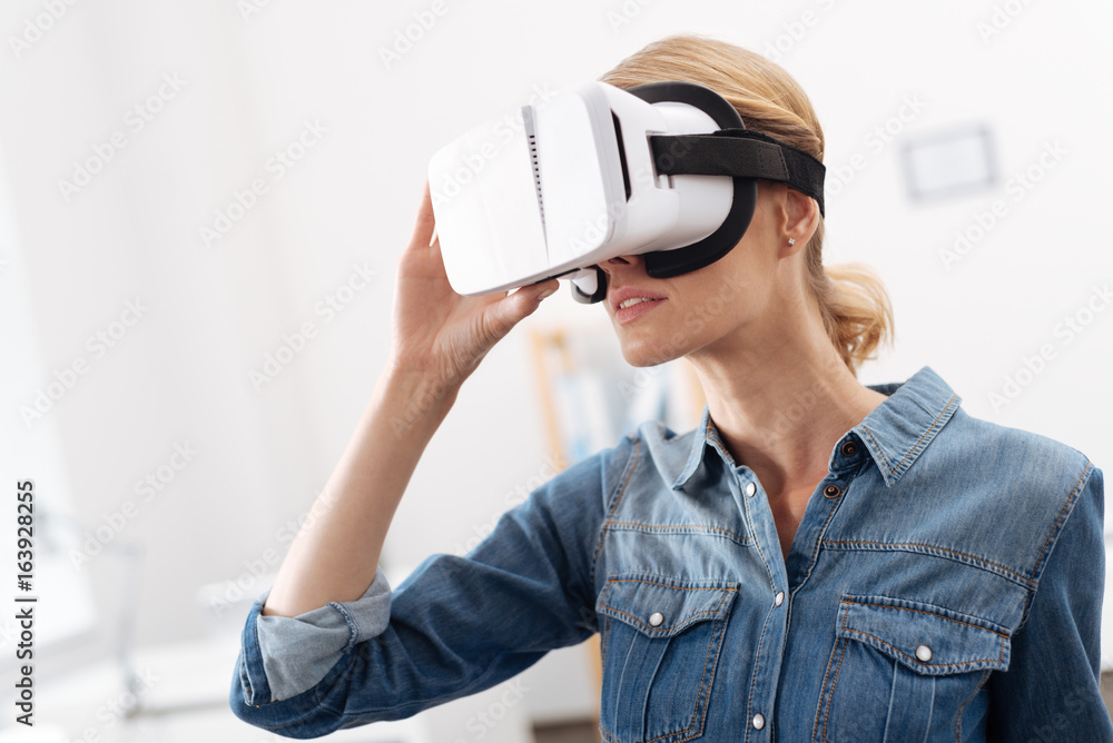 Charming woman using visual reality headset indoors