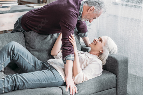 happy senior couple resting on sofa while spending time at home