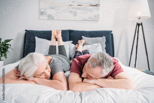 senior wife and husband sleeping in bed together at home