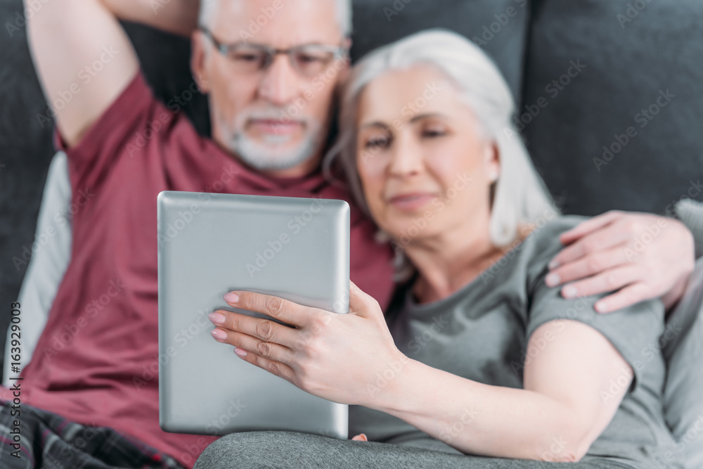 selective focus of senior couple with digital tablet resting in bed together selective focus of senior couple with digital tablet resting in bed together