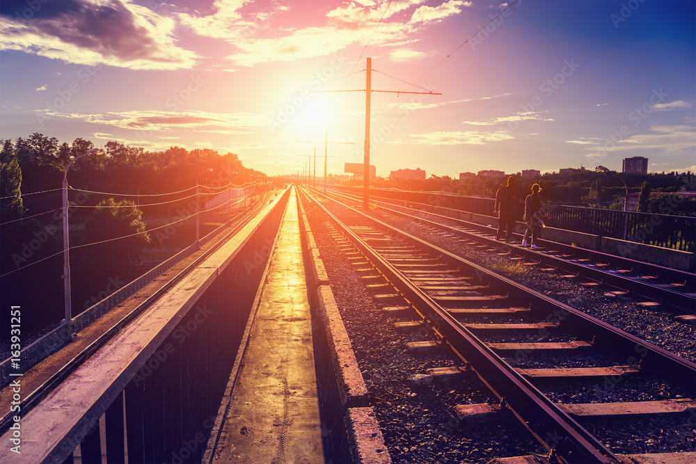Couple goes by rail on a bridge in the rays of the sunset. North Bridge in Voronezh Couple goes by rail on a bridge in the rays of the sunset. North Bridge in Voronezh