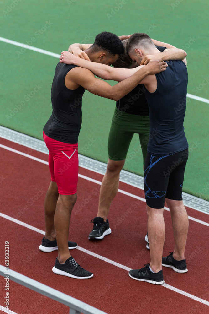 Multiethnic athlete team standing on running track outdoors