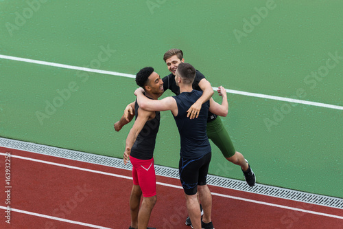 Cheerful multiethnic athlete team standing on running track © Drobot Dean