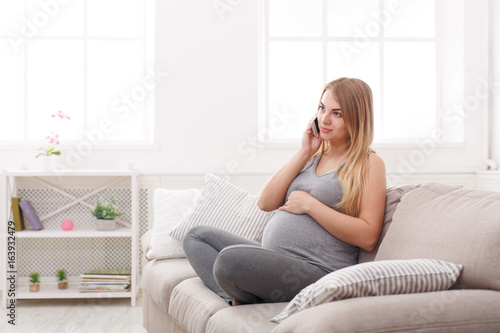 Smiling pregnant woman talking on her smartphone © Prostock-studio