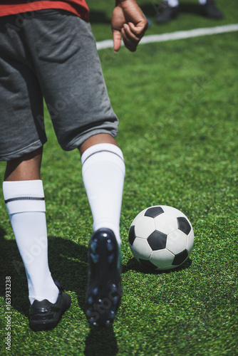 cropped shot of soccer player training with ball on soccer pitch