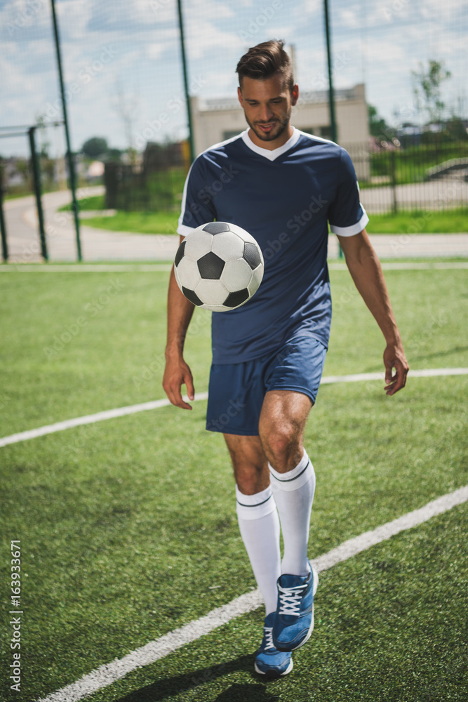 athletic soccer player training with ball on soccer pitch