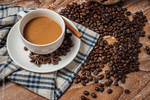 coffee cup with coffee beans on wood table.