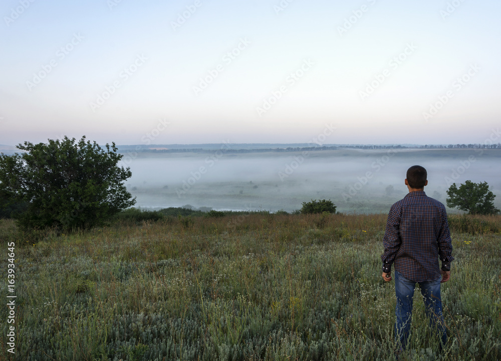 A man stands in a clearing at dawn A man stands in a clearing at dawn