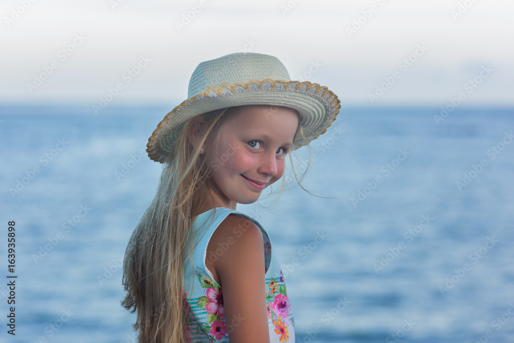 little girl in hat in the beach with horizon of water